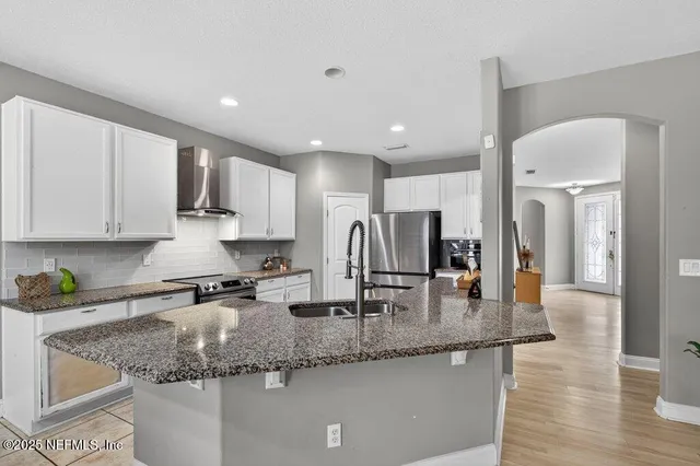 a kitchen with stainless steel appliances granite countertop a sink refrigerator and cabinets