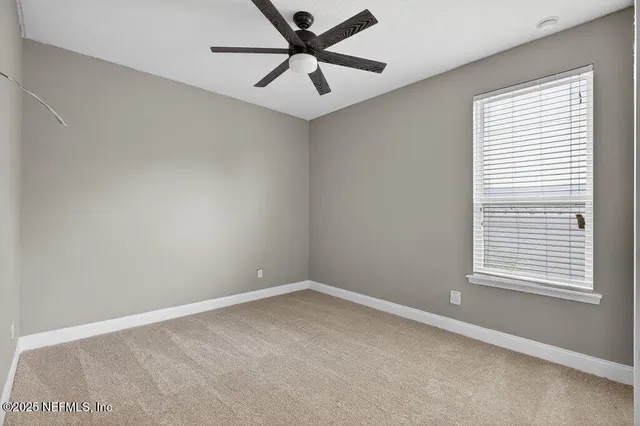 an empty room with a window and a fan