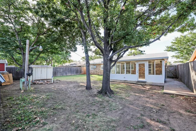a view of a house with a yard and large tree