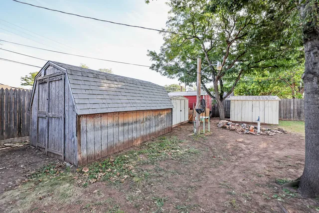 a backyard of a house with a small barn and wooden fence