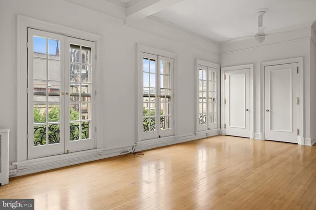 a view of an empty room with a window and wooden floor