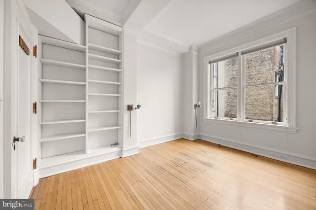 a view of an empty room with a window and wooden floor