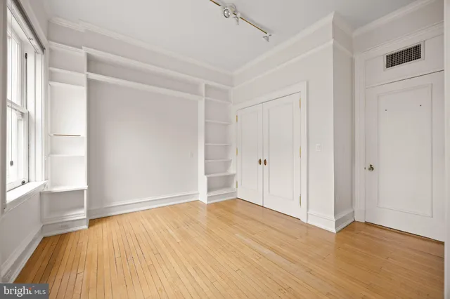 a view of a white house in front of a big yard plants and large trees