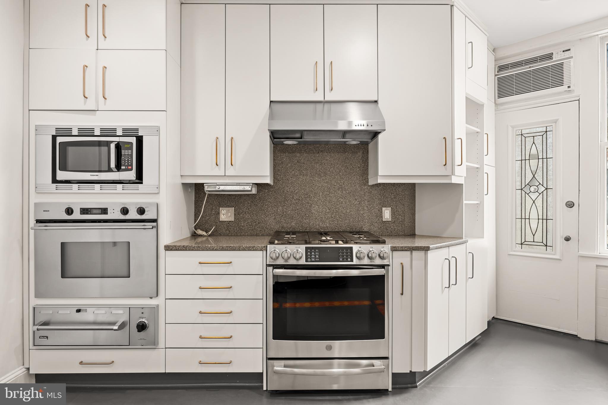 700 Washington Place, Unit 4B Baltimore, MD 21201 - Photo 55 of 67 a kitchen with stainless steel appliances granite countertop white cabinets and a stove a oven with white countertops