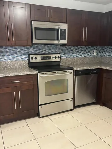 a kitchen with granite countertop a stove top oven microwave and cabinets
