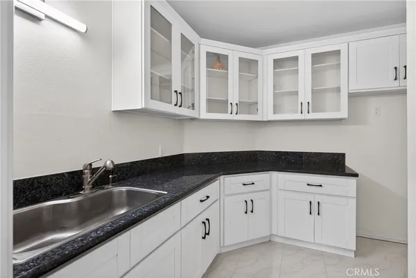 a kitchen with white cabinets and sink
