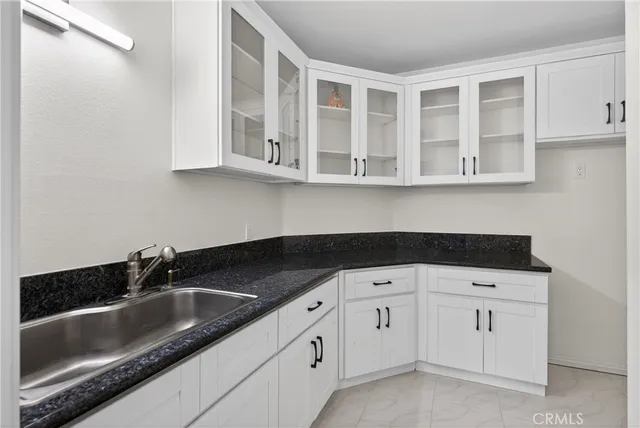a kitchen with white cabinets and sink