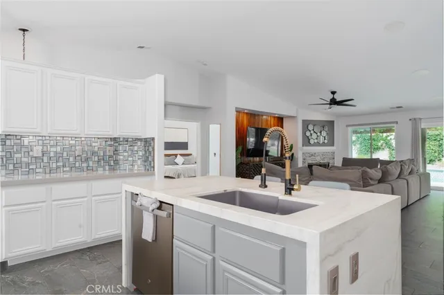 a kitchen with a sink dishwasher and white cabinets with wooden floor