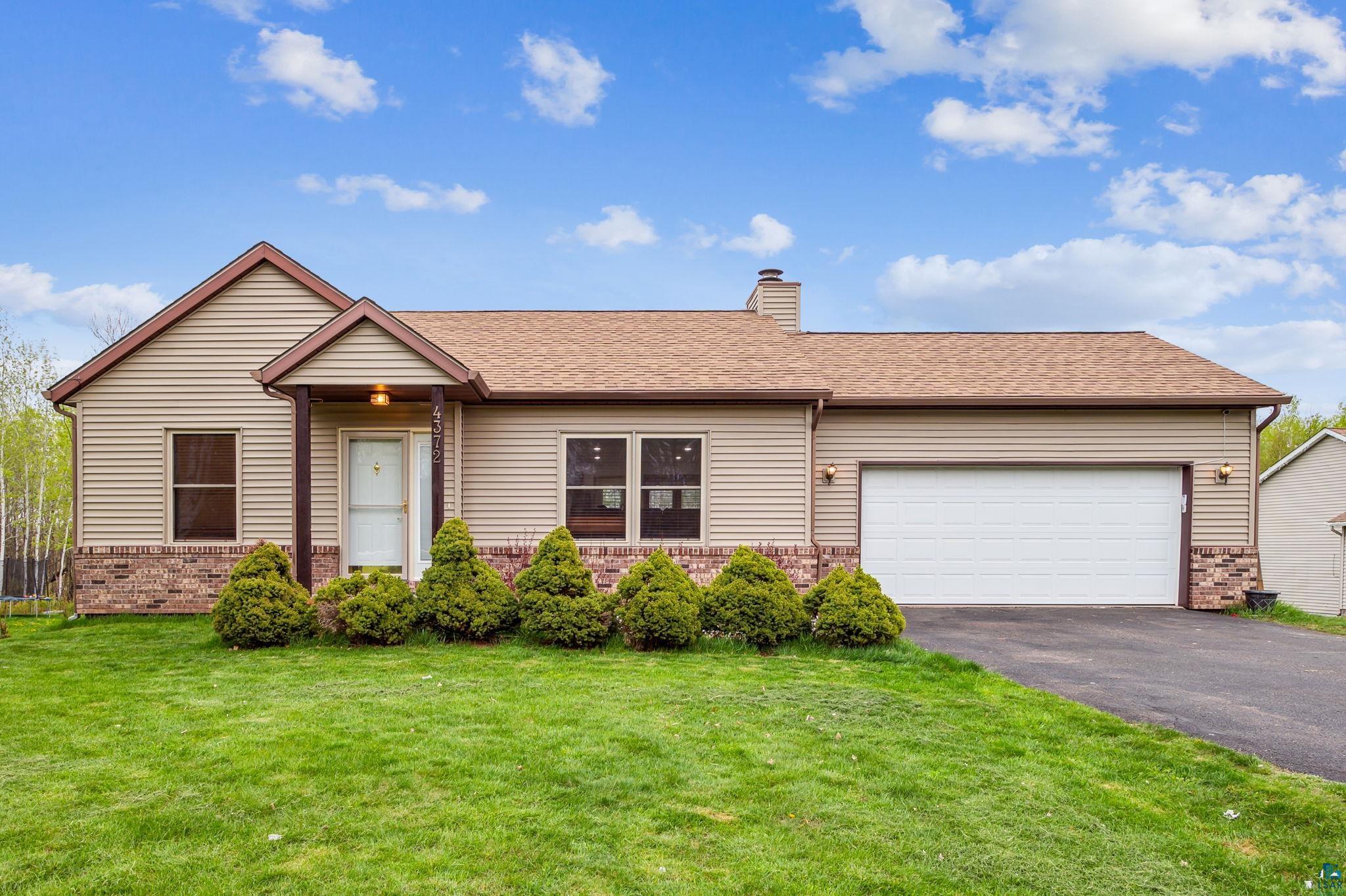 Single story home with a garage and a front yard