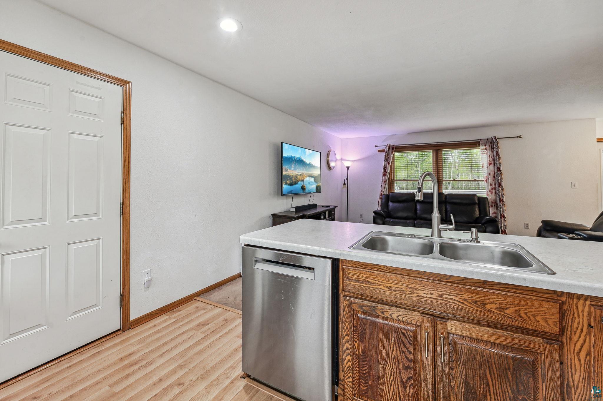 Kitchen with sink, light hardwood / wood-style flooring, and stainless steel dishwasher