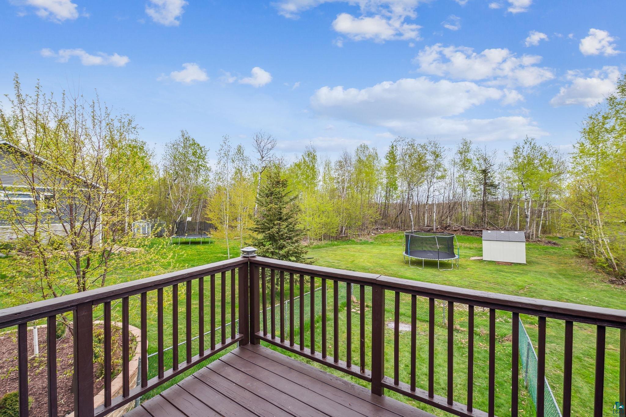 Wooden terrace featuring a trampoline and a yard
