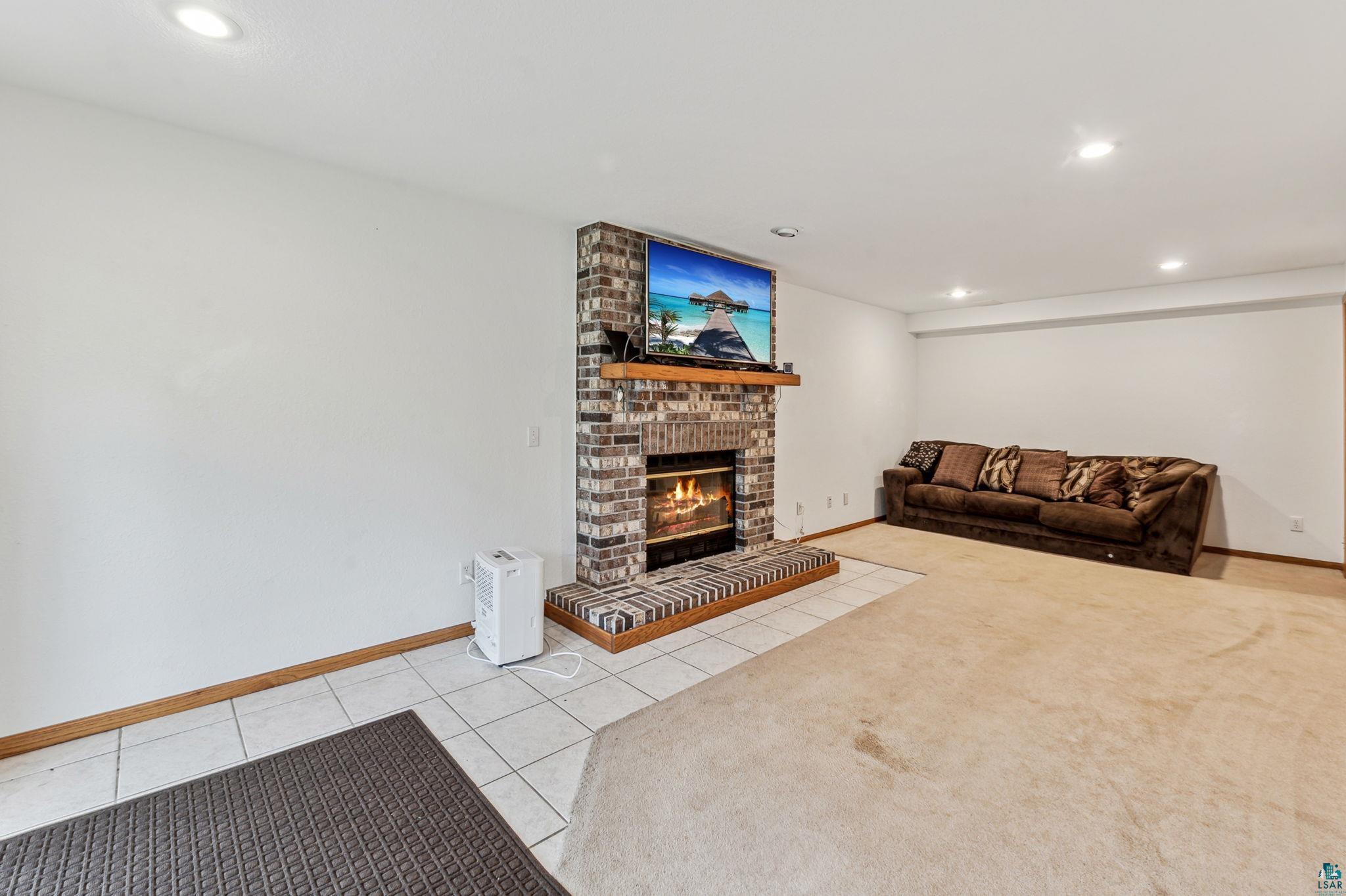 4372 Ugstad Road Hermantown, MN 55811 - Photo 10 of 21 Tiled living room featuring a brick fireplace and brick wall