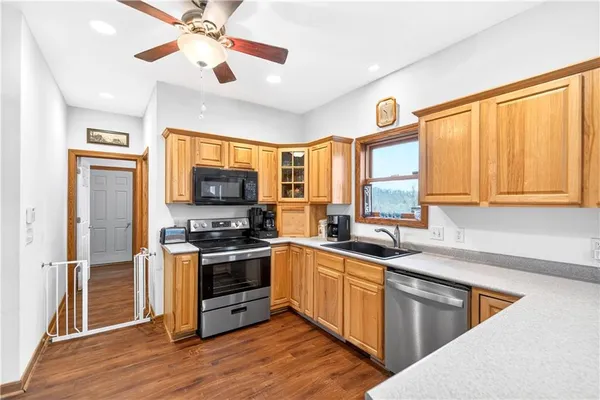 a kitchen with stainless steel appliances granite countertop a stove top oven a refrigerator a sink and dishwasher with wooden floor