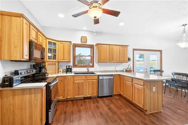 a kitchen with stainless steel appliances granite countertop wooden cabinets a dining table and chairs