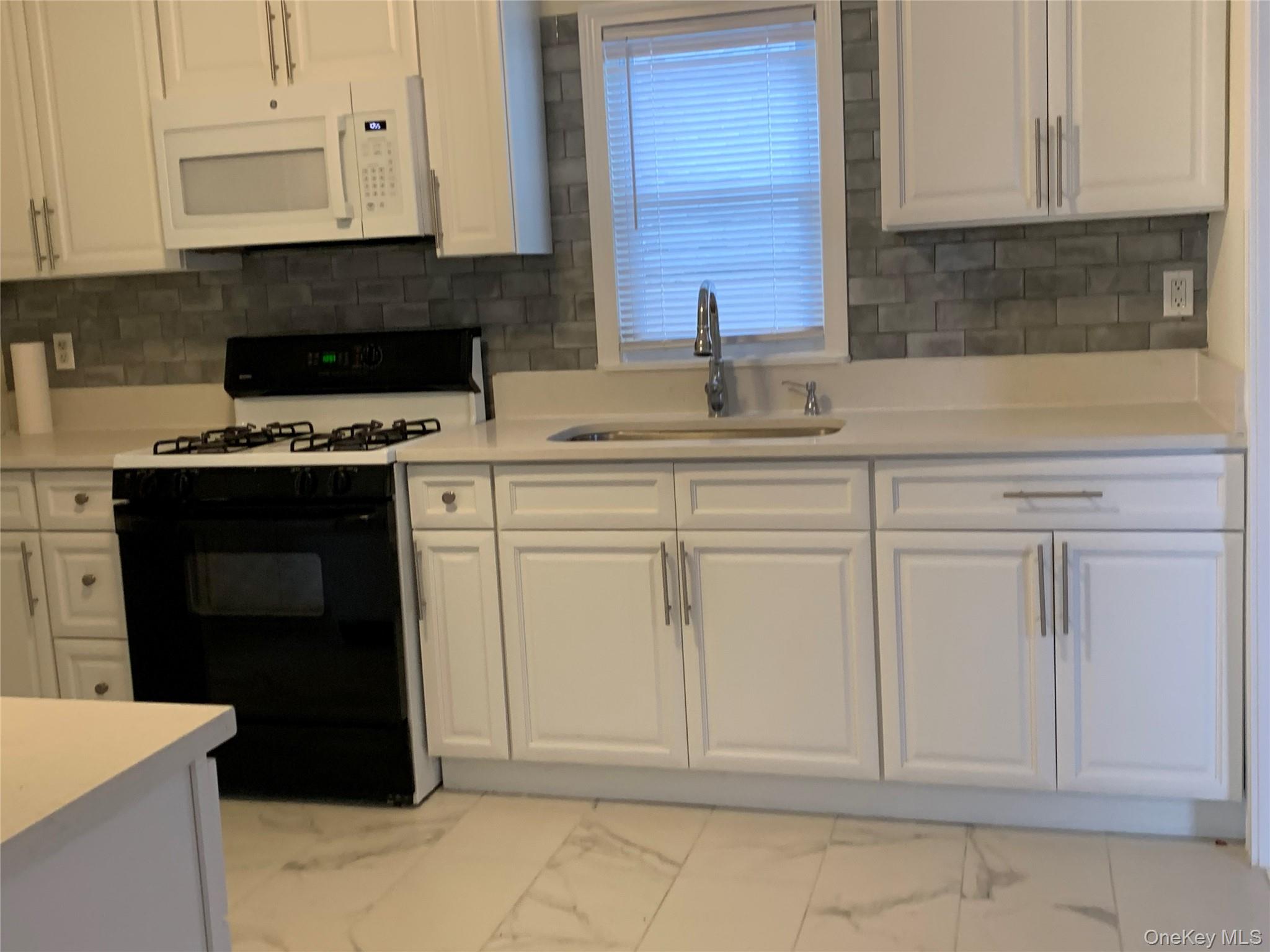 7 Clinton Street Haverstraw, NY 10927 - Photo 5 of 20 Kitchen featuring white cabinetry, light countertops, a gray subway tile backsplash, white over-the-range microwave, and a black range