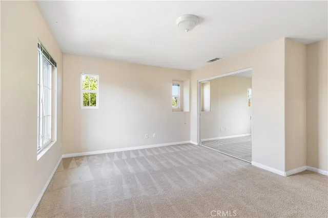 a view of an empty room with window and closet area