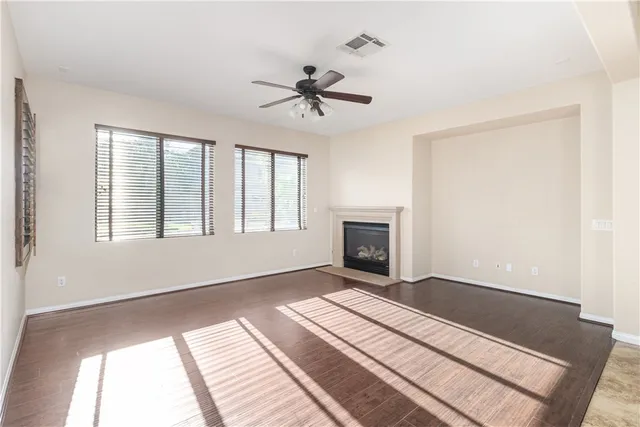 a view of a livingroom with a fireplace a ceiling fan and wooden floor