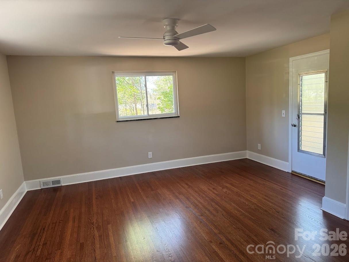 4424 Back Creek Church Road Charlotte, NC 28213 - Photo 13 of 15 an empty room with wooden floor chandelier fan and windows