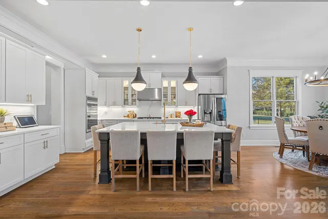 a kitchen with stainless steel appliances kitchen island granite countertop a dining table chairs and white cabinets