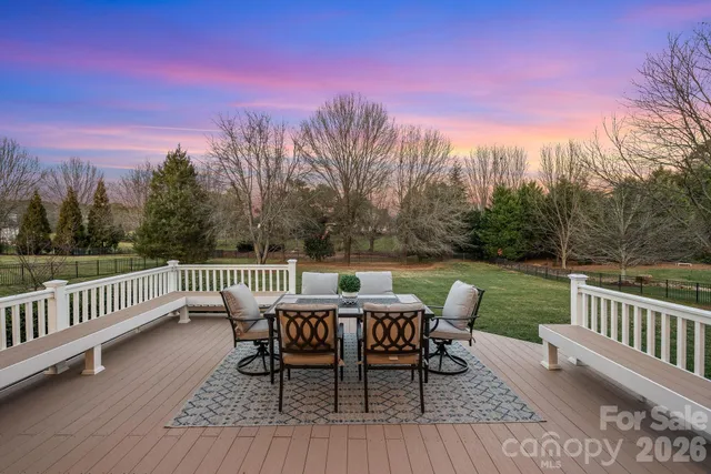 a view of a table and chairs on roof deck with wooden floor and fence