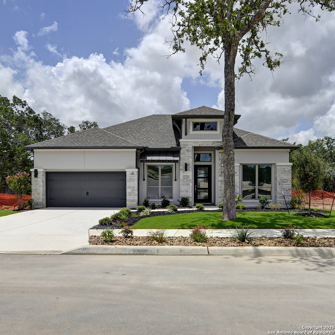 a front view of a house with a garden and trees
