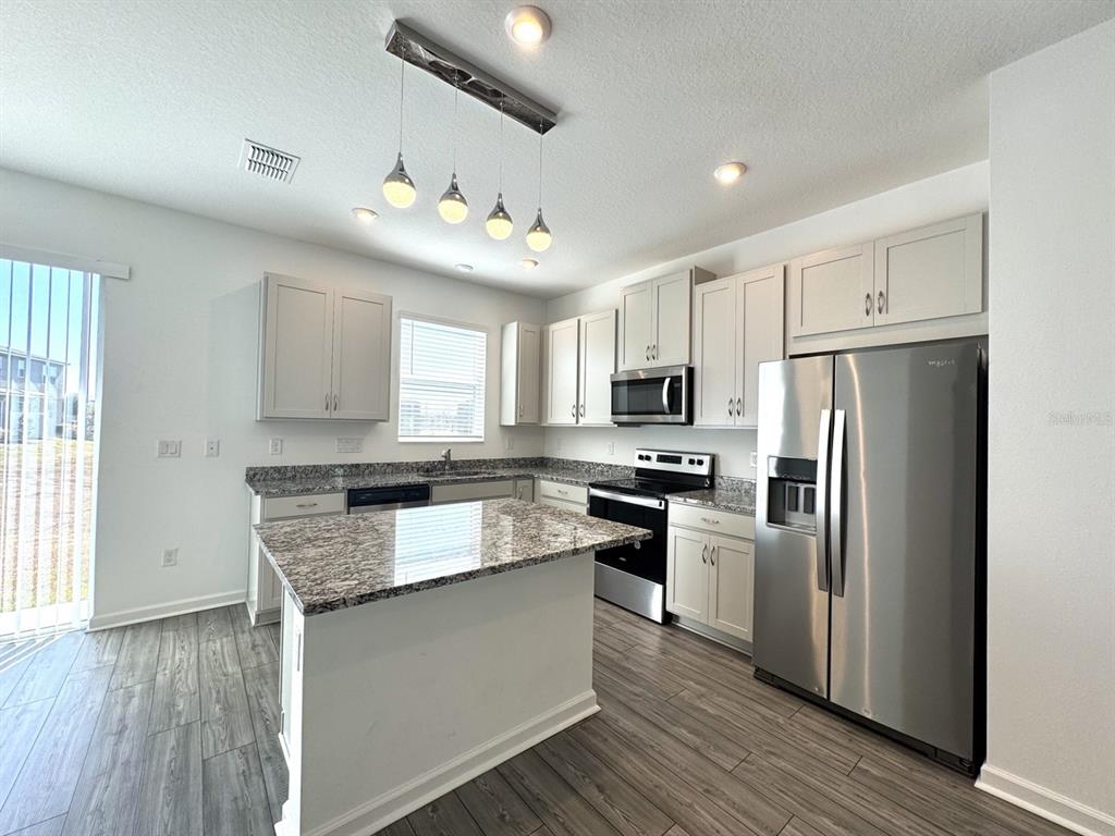 1025 Spring Palms Loop Orlando, FL 32828 - Photo 8 of 9 a kitchen with granite countertop a refrigerator stove top oven and sink