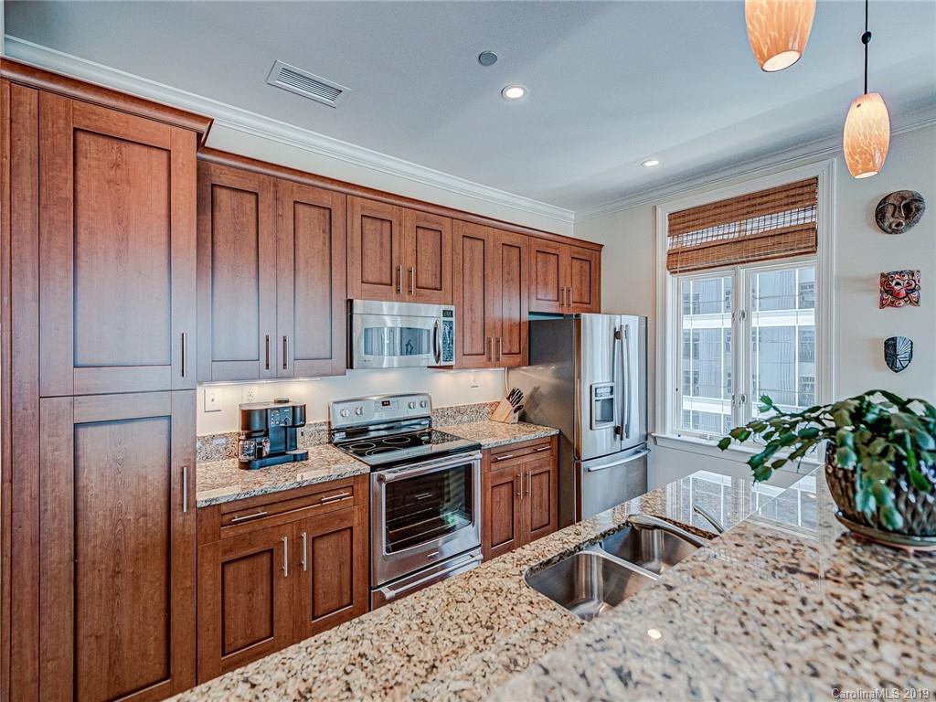 230 South Tryon Street, Unit 710 Charlotte, NC 28202 - Photo 11 of 48 a kitchen with stainless steel appliances granite countertop a refrigerator a stove a sink dishwasher and wooden cabinets with wooden floor