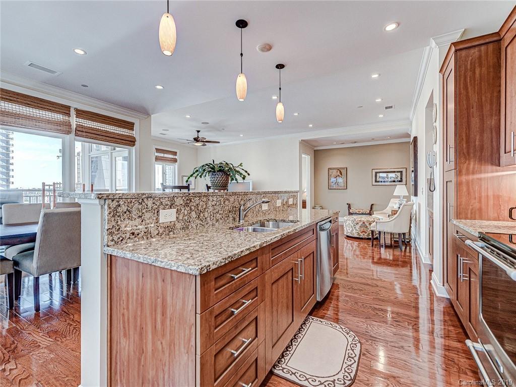 230 South Tryon Street, Unit 710 Charlotte, NC 28202 - Photo 14 of 48 an open kitchen with granite countertop a stove and white cabinets