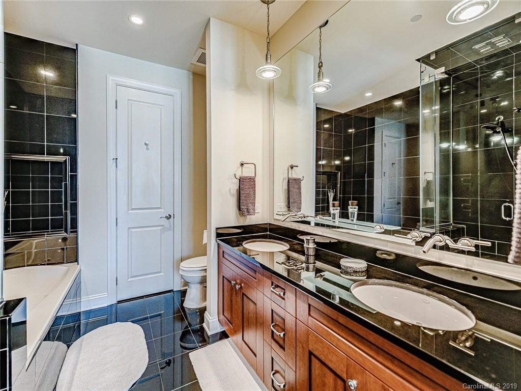 230 South Tryon Street, Unit 710 Charlotte, NC 28202 - Photo 23 of 48 a bathroom with a granite countertop sink a toilet a mirror and shower