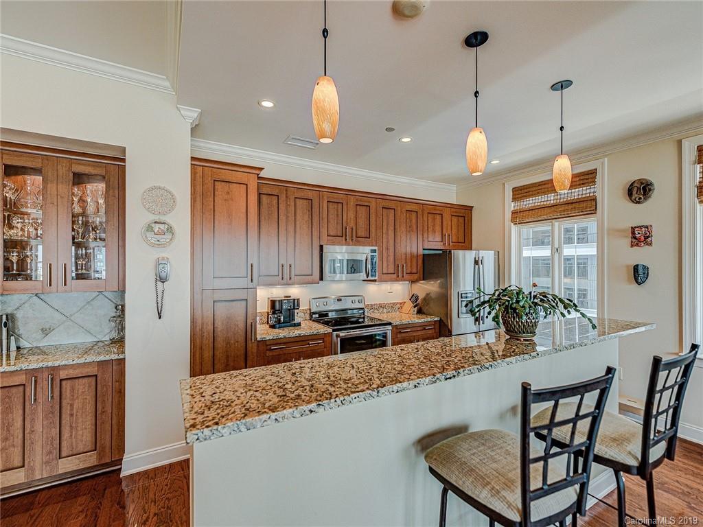 230 South Tryon Street, Unit 710 Charlotte, NC 28202 - Photo 10 of 48 a kitchen with granite countertop a stove a sink a dining table and chairs