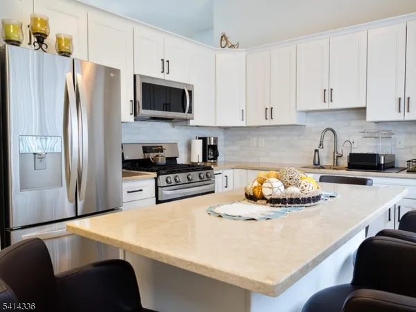 a kitchen with stainless steel appliances white cabinets and wooden floor