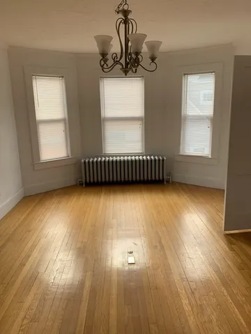 a view of empty room with wooden floor and a window