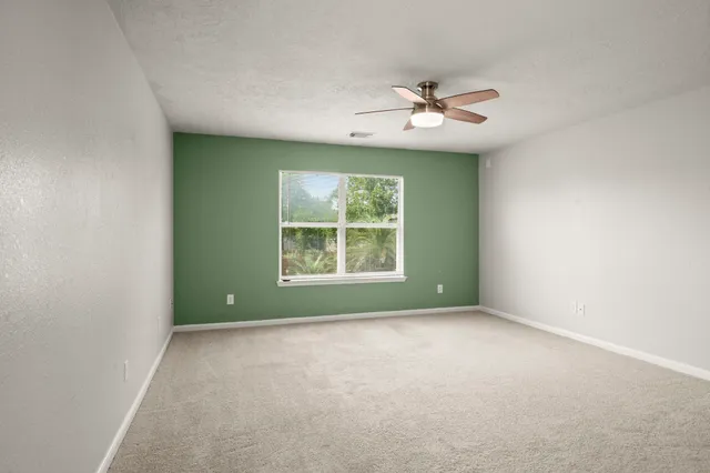 an empty room with windows and ceiling fan