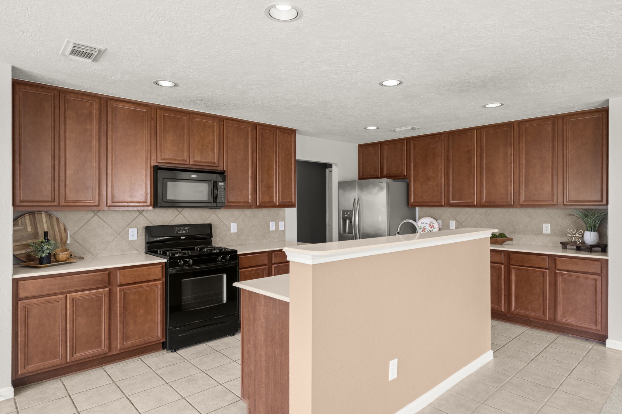 19819 Rippling Brook Lane Tomball, TX 77375 - Photo 5 of 29 a kitchen with stainless steel appliances granite countertop a stove top oven a sink dishwasher and a refrigerator with wooden cabinets