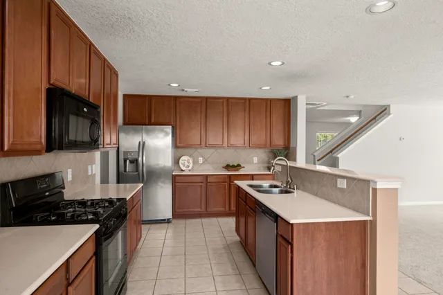 a kitchen with stainless steel appliances granite countertop a sink stove refrigerator and cabinets