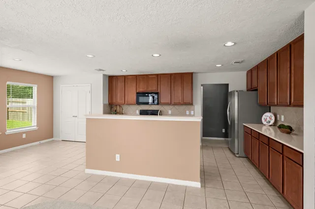 a living room with stainless steel appliances a refrigerator a sink a counter top space and cabinets