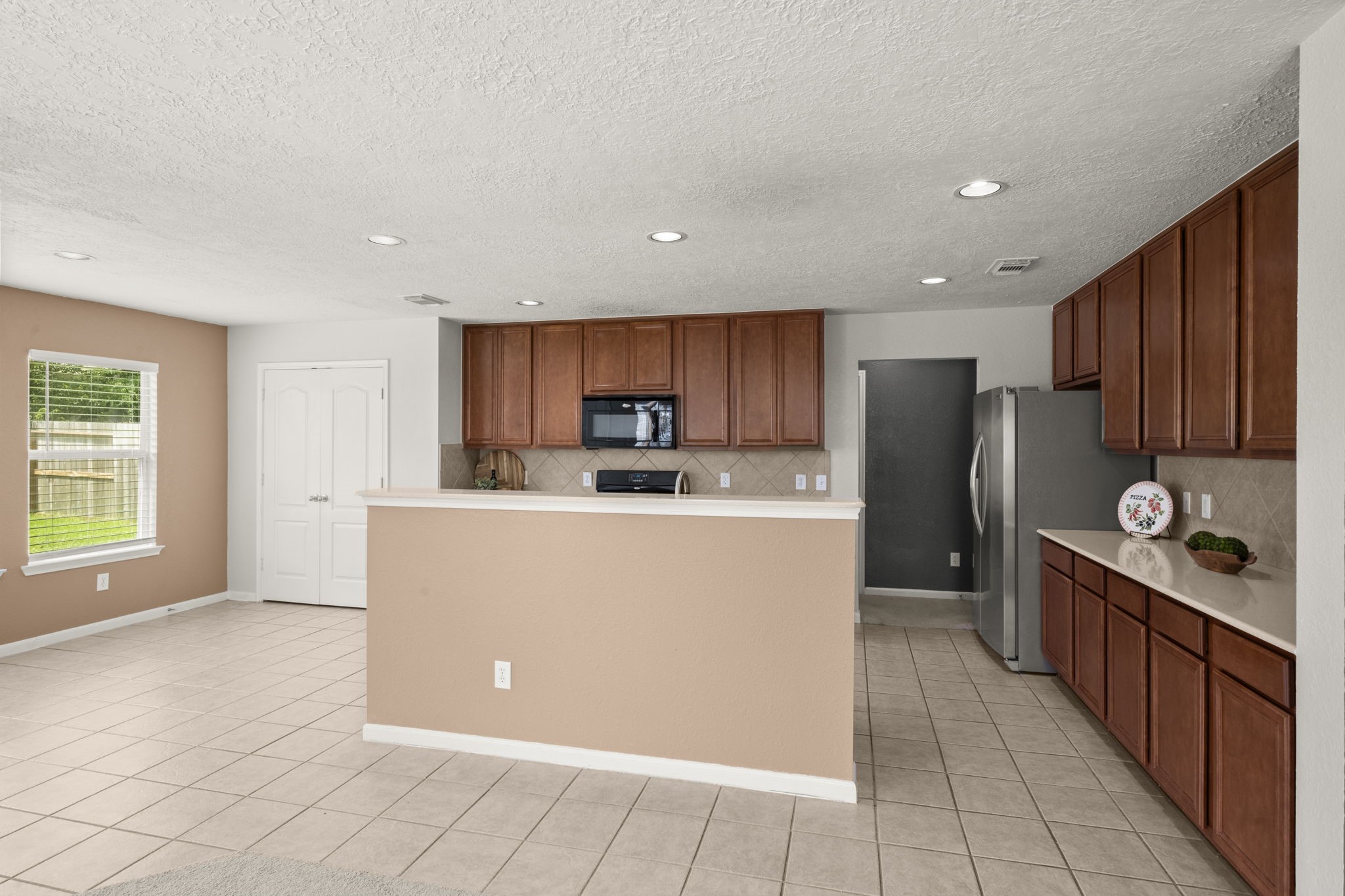 19819 Rippling Brook Lane Tomball, TX 77375 - Photo 7 of 29 a living room with stainless steel appliances a refrigerator a sink a counter top space and cabinets
