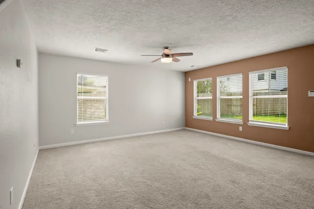 an empty room with windows and ceiling fan