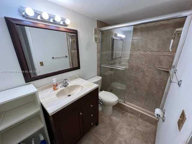 a bathroom with a sink vanity granite toilet and a mirror
