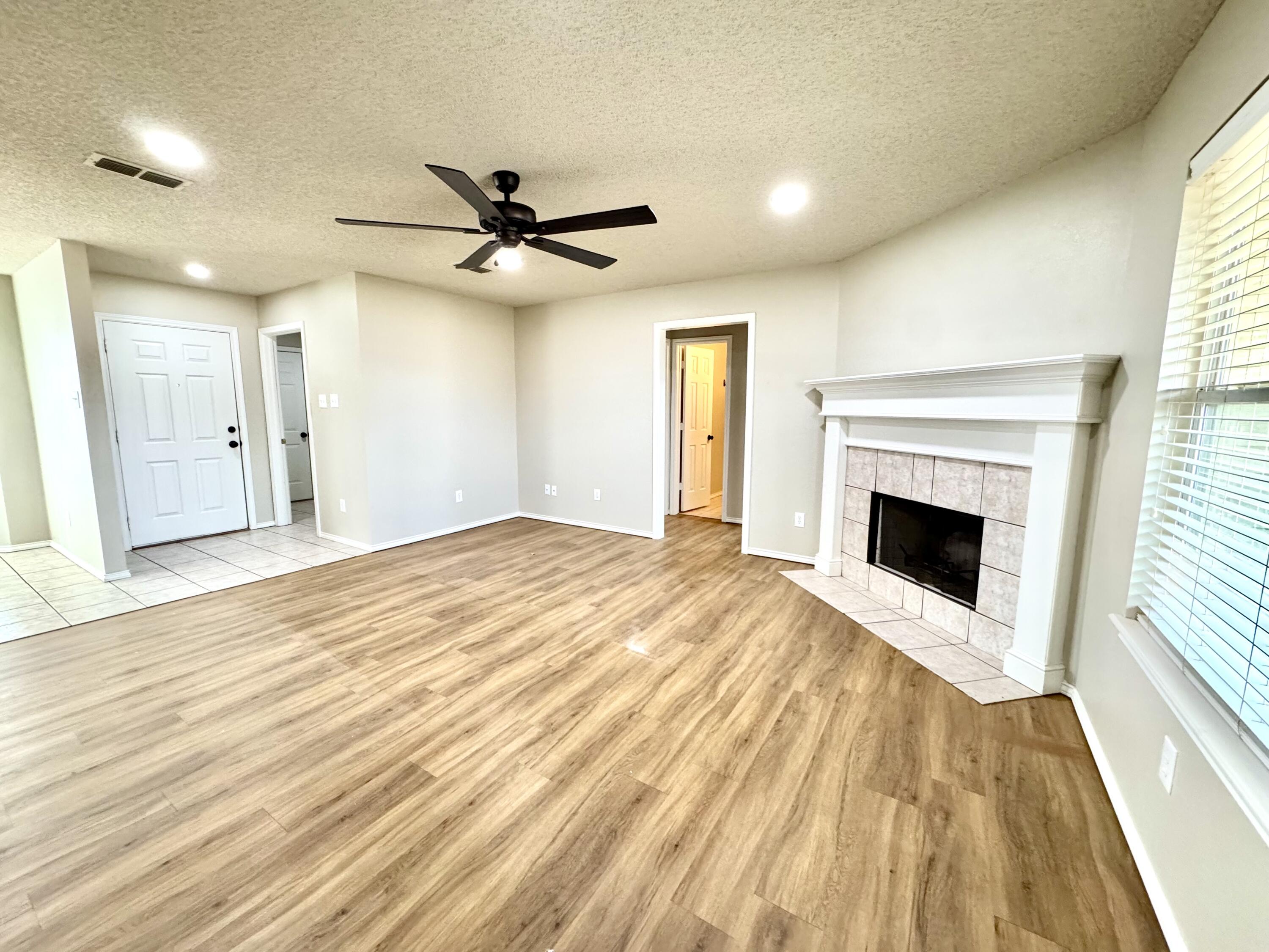 6536 7th Street Lubbock, TX 79416 - Photo 4 of 20 a view of a livingroom with a fireplace a ceiling fan and wooden floor