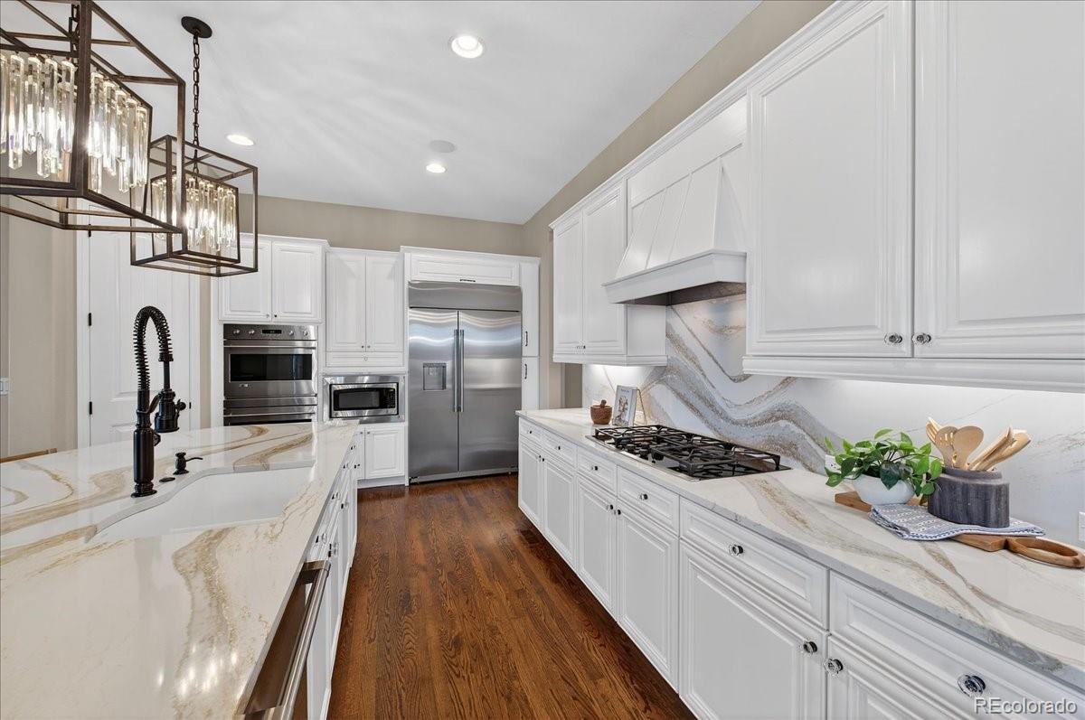10693 Featherwalk Way Highlands Ranch, CO 80126 - Photo 12 of 50 a kitchen with stainless steel appliances kitchen island granite countertop a refrigerator and a stove top oven