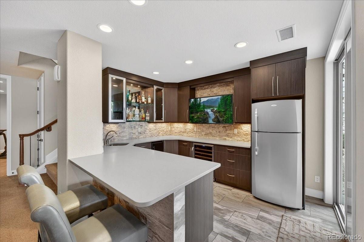 10693 Featherwalk Way Highlands Ranch, CO 80126 - Photo 34 of 50 a kitchen with stainless steel appliances granite countertop a refrigerator a sink a stove a dining table and chairs