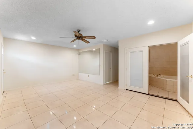 a view of an empty room and chandelier fan