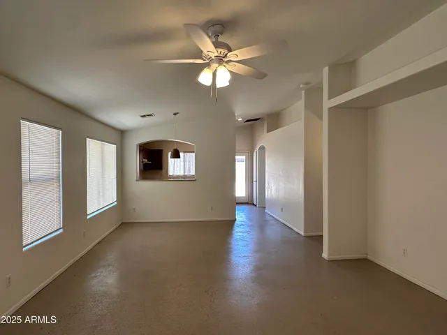 a view of an empty room with window and a kitchen