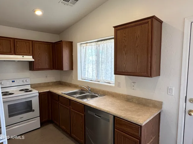 a kitchen with granite countertop stainless steel appliances a stove sink and cabinets