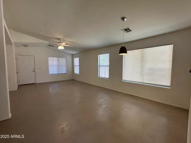an empty room with windows and ceiling fan