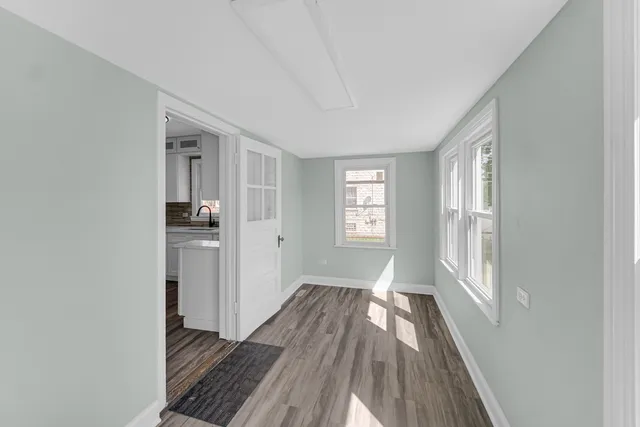a view of a room with wooden floor electronic appliances and windows