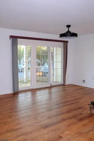 a view of an empty room with a window and wooden floor