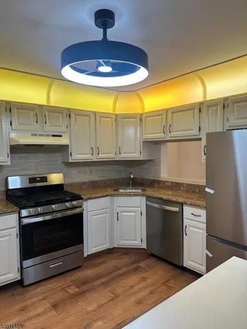 a view of a kitchen with stainless steel appliances wooden floor and a window
