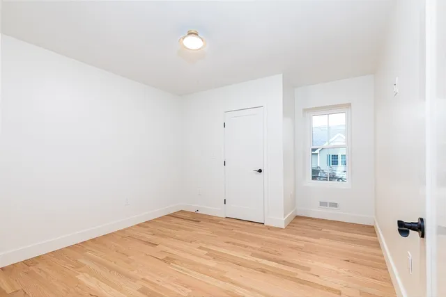a bedroom with bed and a potted plant next to a window